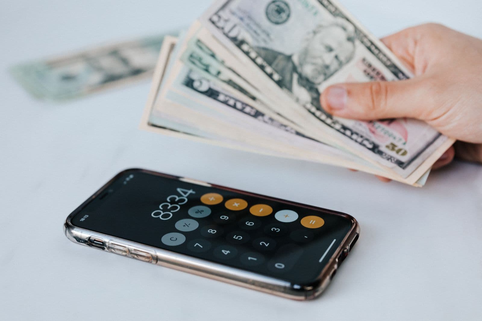 Manos contando dinero junto a una calculadora